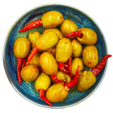 A rustic blue dish filled with vibrant yellow west country hot chilli olives 175g and bright red south devon chilli peppers