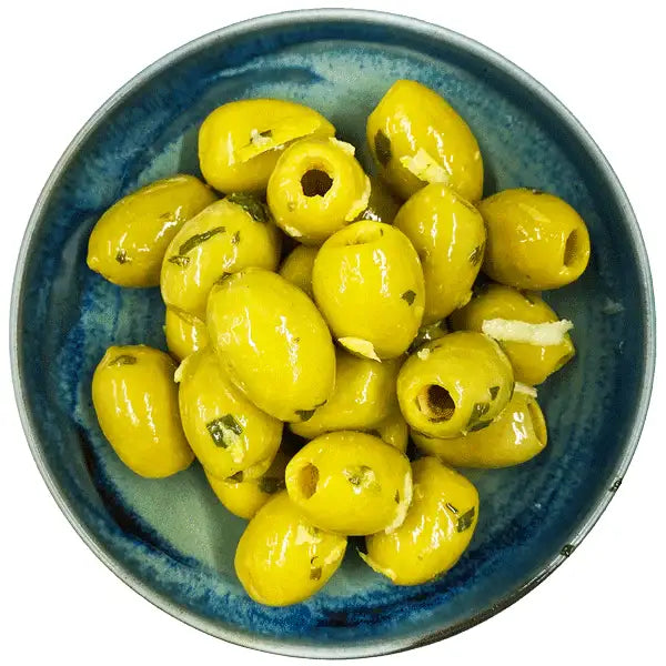 A bowl of vibrant green west country lemon and tarragon olives halved to show creamy delphi stuffed filling with herbs