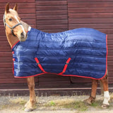 Blue quilted stable rug 250gm with red trim and straps from whitaker thomas stable rug collection