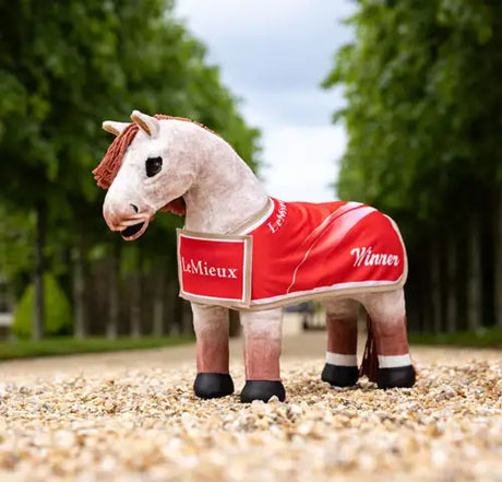 A white plush horse figurine wearing a red racing blanket with ’lemieux’ and ’winner’ embroidered in white.