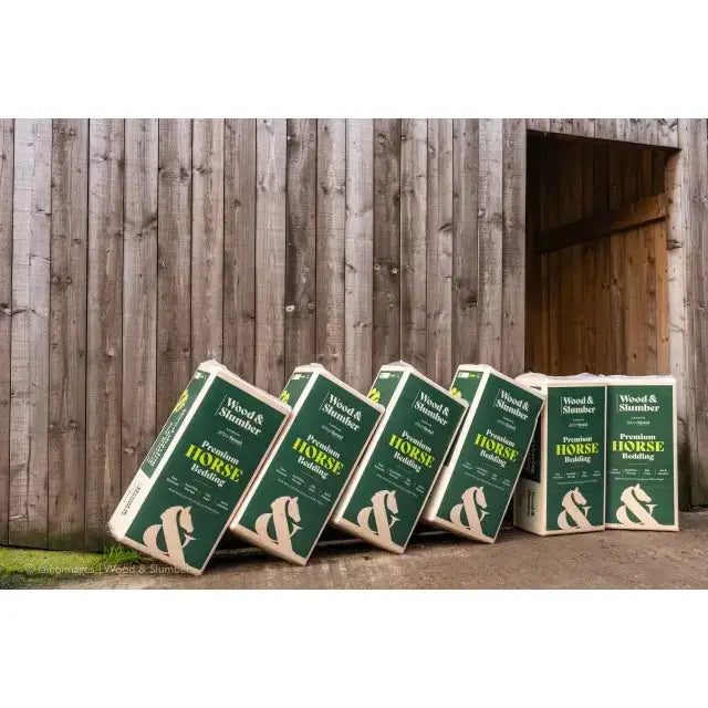 Green and white boxes of Wood and Slumber premium horse bedding mix with small flake slumber wood shavings and horse logo