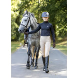A rider in a black woof wear young rider tech shirt with iflex fabric walks beside a dapple gray horse wearing a dark helmet