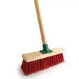 Yard broom fitted with red pvc bristles wooden handle and green metal ferrule for outdoor cleaning tasks