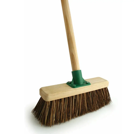 A yard broom stiff base with a wooden handle green plastic connector and handy stiff bristle brown bristles