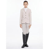 A young girl wearing a lemieux young rider kennedy show jacket stone in beige with black buttons and equestrian boots
